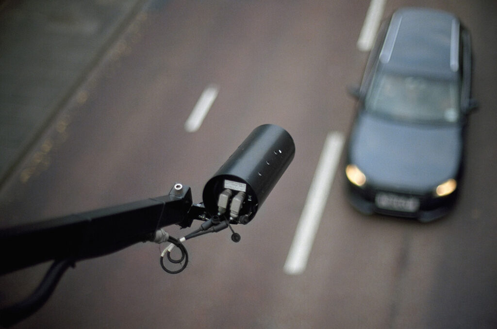 A camera pointing down at a car that is driving down a road