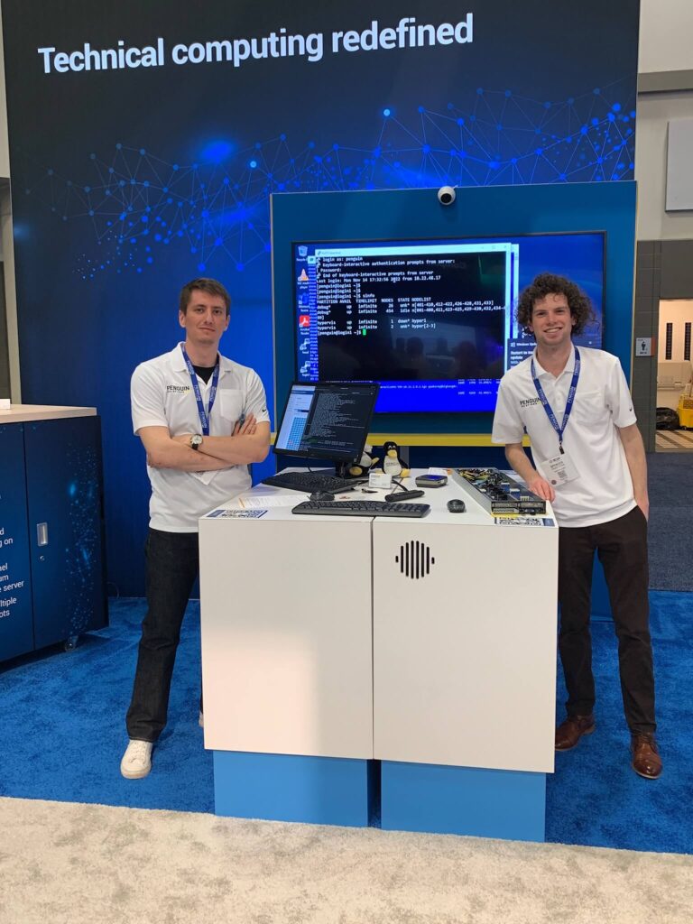 Two Penguin employees in front of a computer, server, and large screen performing a demo.